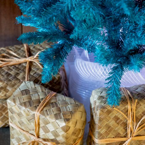 A blue tinsel decoration arches over several woven straw baskets, with a small glowing light reflecting through them.