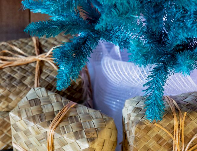A blue tinsel decoration arches over several woven straw baskets, with a small glowing light reflecting through them.